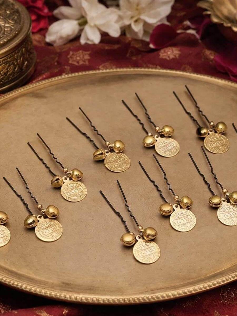 A set of coin and bell hair pins laid out on a brass tray